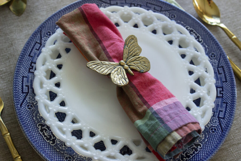 Tablescape with blue willow and white milk glass plate and butterfly napkin ring