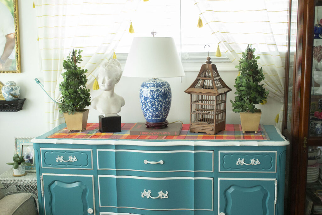 Turquoise blue buffet table  styled with a blue and white porcelain lamp and topiaries