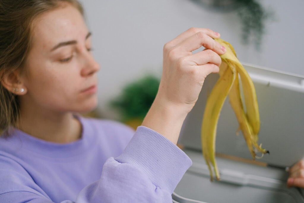 Woman tossing banana peel into compost pile