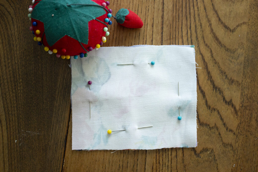 Fabric Square with sewing pins and red pincushion