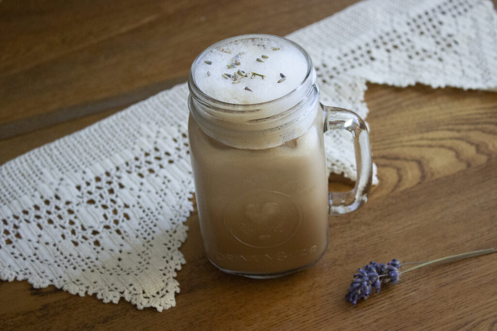 Iced Lavender Honey Latte with lace and lavender stems in the backdrop