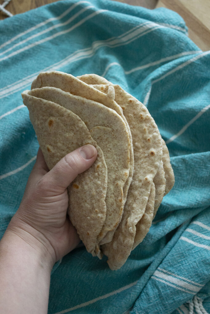 Easy Whole Wheat Tortilla Recipe: Hand holding flour tortillas