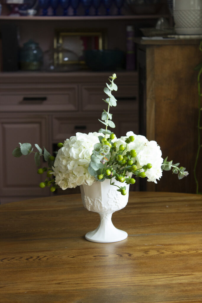How to Arrange Flowers: White hydrangea floral arrangement in white footed vase