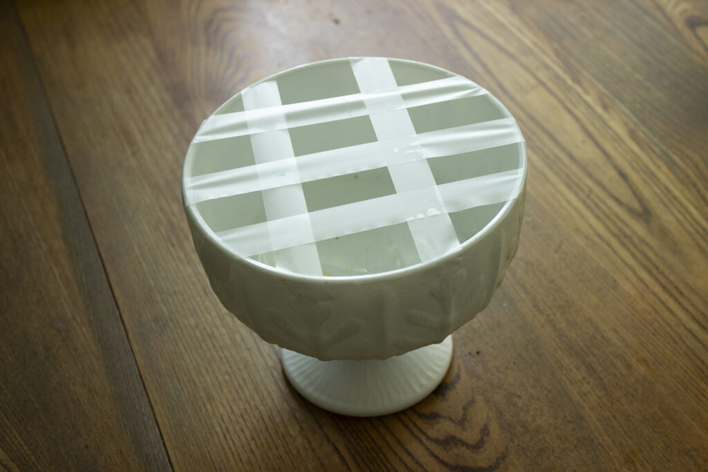 Tape grid over the top of a white pedestal vase