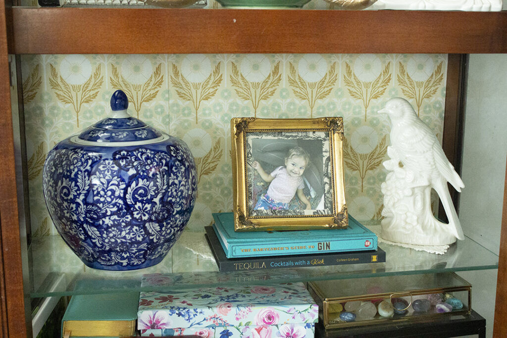 How to Style a China Cabinet: China Cabinet Shelf with blue jar, gold frame, and white bird figurine