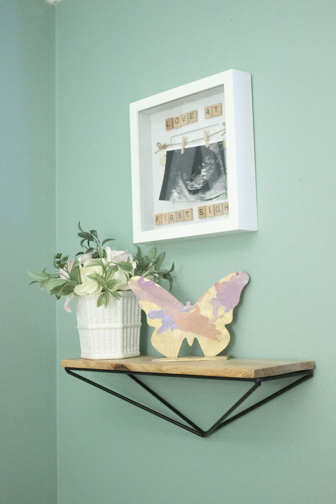 Shelf with wooden butterfly and floral arrangement