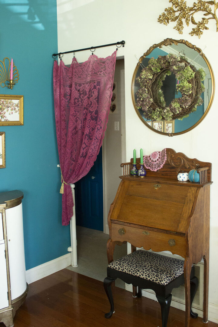 living room corner with a secretary desk and pink curtain in the doorway